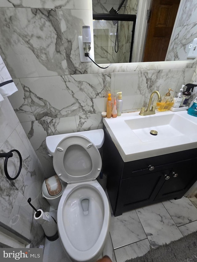 full bath featuring marble finish floor, vanity, a shower stall, and toilet