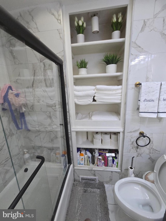 full bathroom featuring marble finish floor, built in shelves, a shower with door, and tile walls