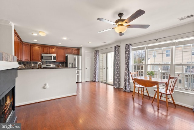 kitchen with stainless steel appliances, a peninsula, dark wood-style floors, tasteful backsplash, and dark countertops