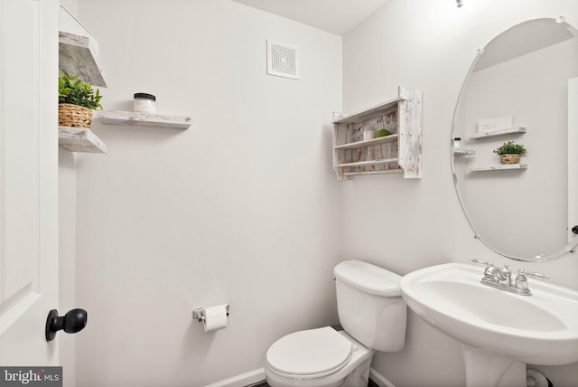 half bathroom featuring visible vents, a sink, toilet, and baseboards