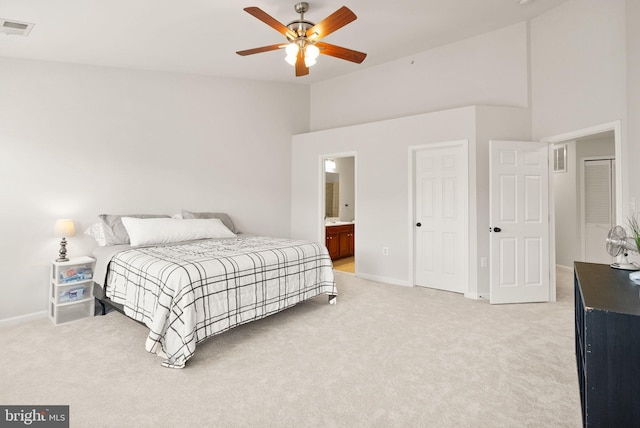 bedroom with light carpet, baseboards, visible vents, and ensuite bathroom