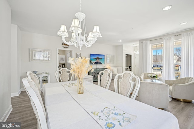 dining space with recessed lighting, baseboards, an inviting chandelier, and wood finished floors