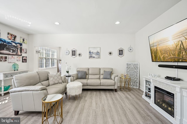 living room featuring a glass covered fireplace, wood finished floors, and recessed lighting