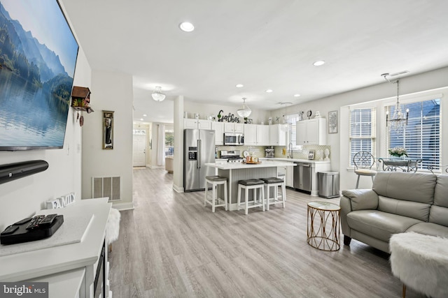 living room with light wood-style flooring, visible vents, a notable chandelier, and recessed lighting