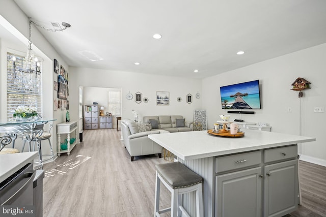 kitchen with gray cabinets, a healthy amount of sunlight, a kitchen island, and light wood finished floors