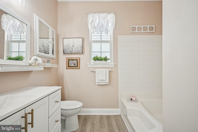 bathroom with a wealth of natural light, vanity, baseboards, and wood finished floors