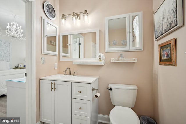 ensuite bathroom with toilet, connected bathroom, a notable chandelier, and vanity