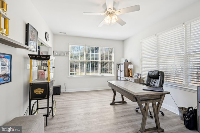 office featuring ceiling fan, visible vents, baseboards, and wood finished floors