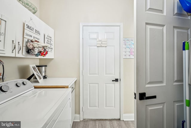 laundry area with light wood-style flooring, independent washer and dryer, cabinet space, and baseboards