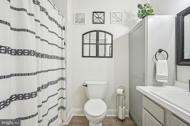 full bathroom featuring baseboards, vanity, toilet, and wood finished floors