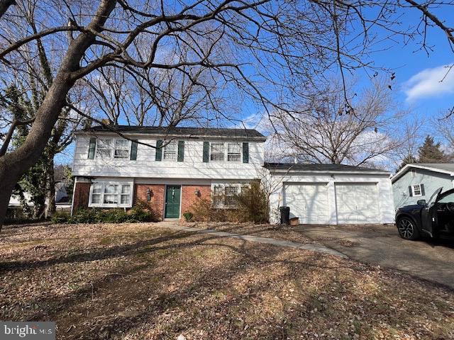 colonial house featuring concrete driveway, brick siding, and an attached garage