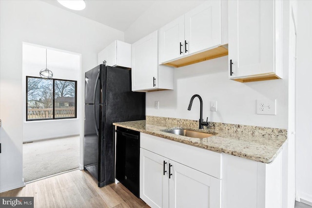 kitchen featuring white cabinetry, black appliances, light stone counters, and a sink