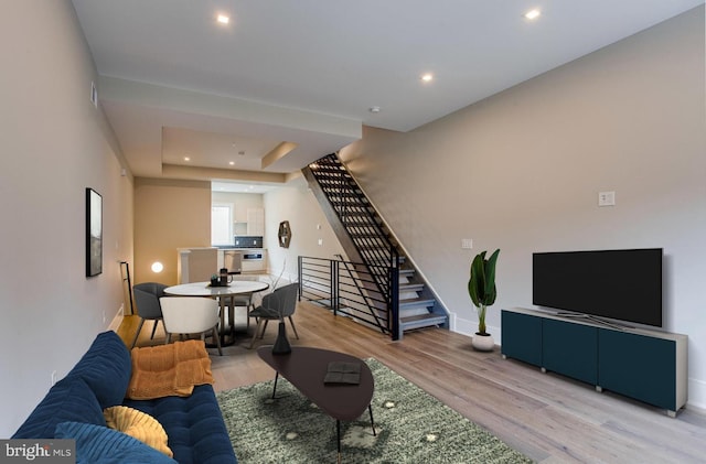 living room featuring light wood-style floors, recessed lighting, stairway, and baseboards