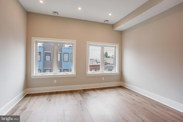 empty room featuring light wood finished floors, recessed lighting, visible vents, and baseboards