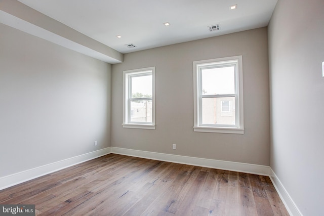 unfurnished room featuring light wood-type flooring, visible vents, and baseboards