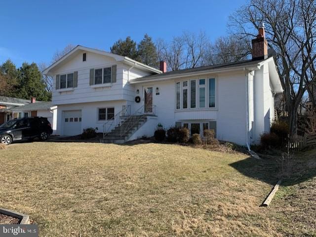 tri-level home with a garage, a front yard, and a chimney