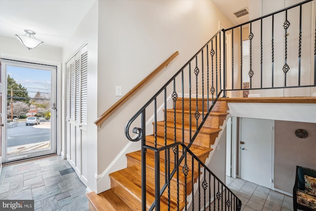 stairway featuring baseboards, visible vents, and stone finish flooring