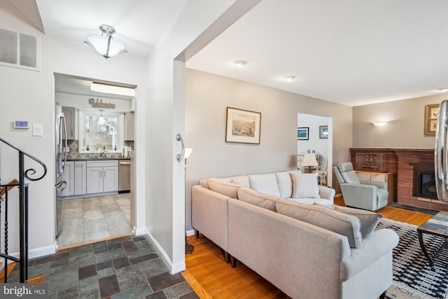 living area with a glass covered fireplace, visible vents, baseboards, and stairs