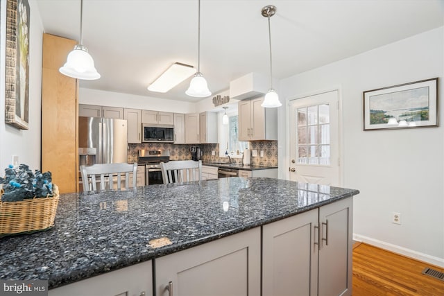 kitchen featuring stainless steel appliances, wood finished floors, visible vents, backsplash, and pendant lighting