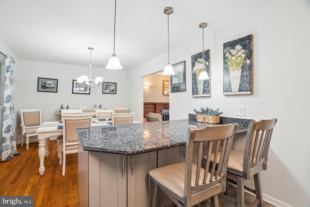 kitchen with dark stone counters, decorative light fixtures, a peninsula, and wood finished floors