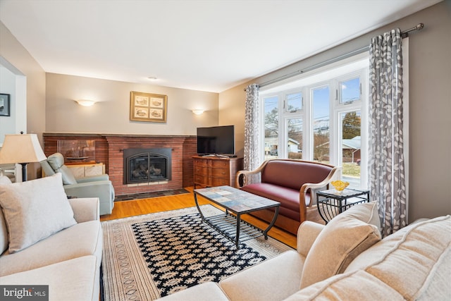 living area with a brick fireplace and wood finished floors