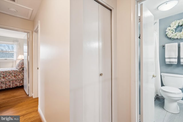 bathroom featuring toilet, baseboards, connected bathroom, and wood finished floors