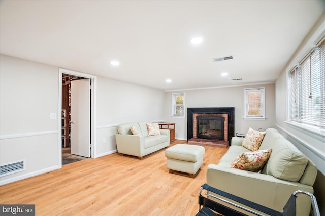 living area with recessed lighting, a brick fireplace, visible vents, and wood finished floors