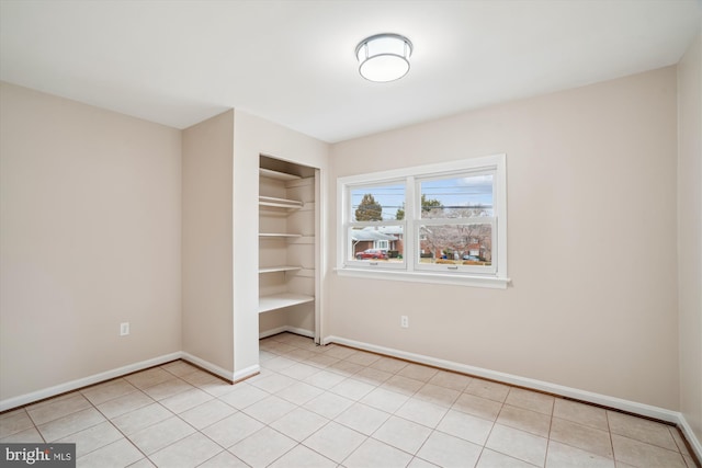 unfurnished bedroom with a closet, light tile patterned flooring, and baseboards