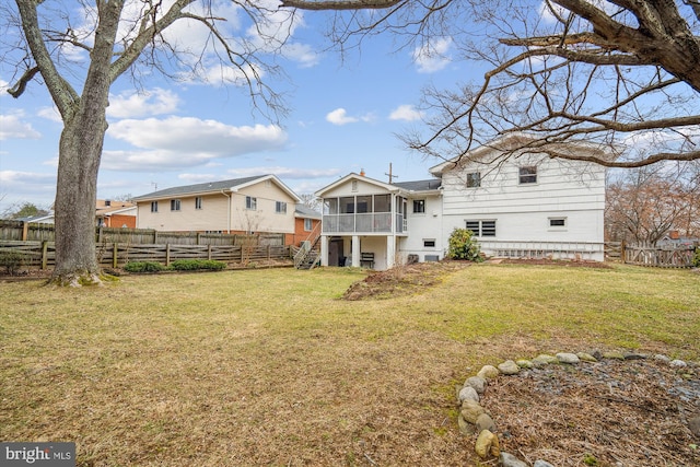 rear view of house with a sunroom, a fenced backyard, and a lawn