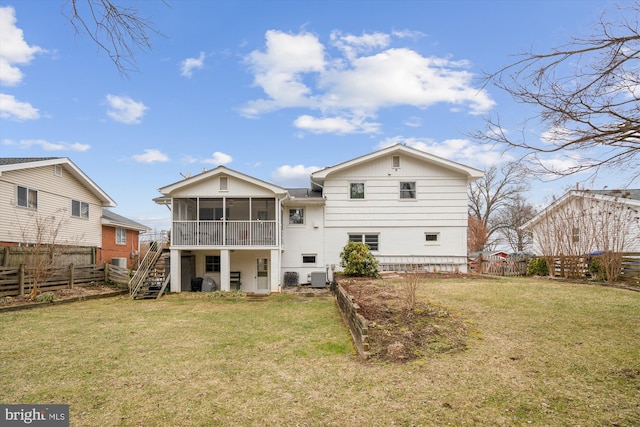 rear view of house featuring a sunroom, a fenced backyard, a yard, and stairs