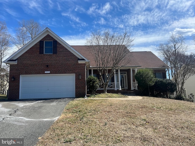 view of front of house featuring aphalt driveway, a porch, a front lawn, and brick siding