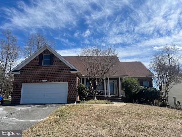 view of front of home with driveway, a garage, brick siding, a porch, and a front yard