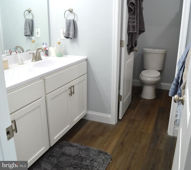 bathroom with baseboards, vanity, toilet, and wood finished floors