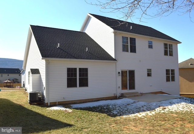 rear view of property with roof with shingles, a patio, a lawn, central AC unit, and entry steps