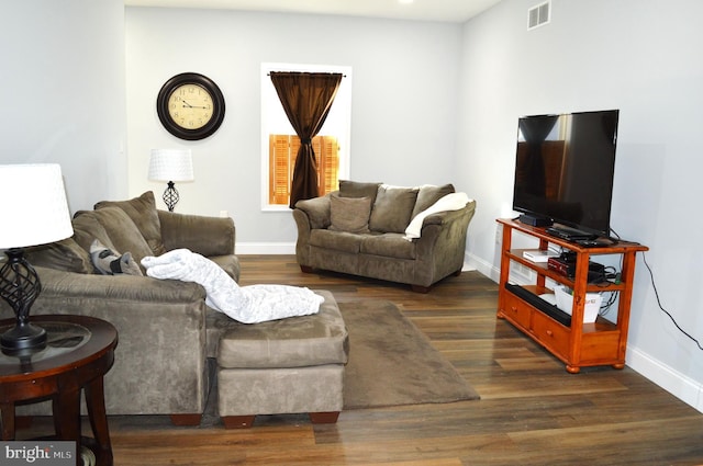 living area featuring dark wood-type flooring, visible vents, and baseboards