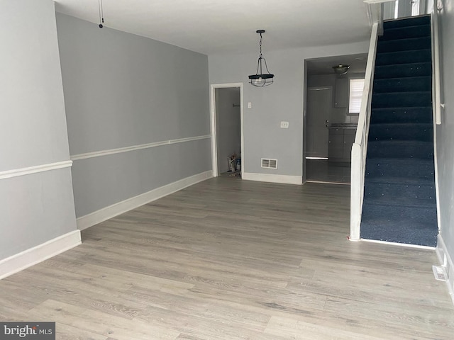 unfurnished dining area featuring stairway, baseboards, visible vents, and wood finished floors