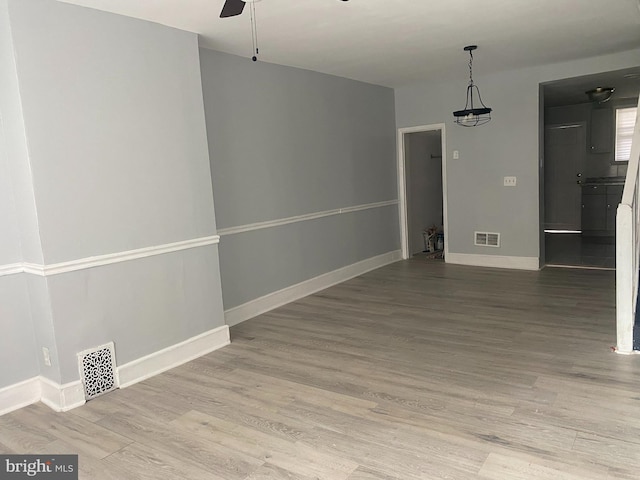 empty room featuring visible vents, baseboards, and wood finished floors