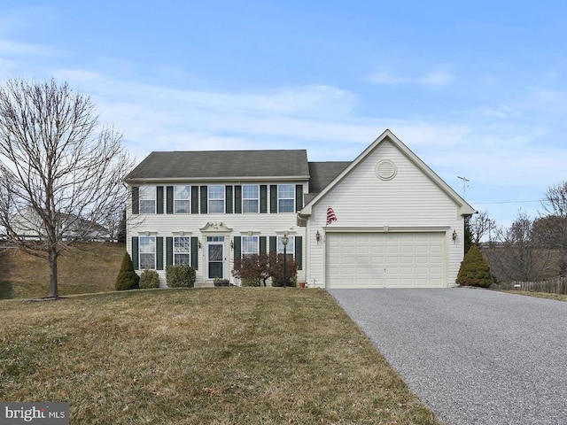 colonial-style house with driveway, an attached garage, and a front yard