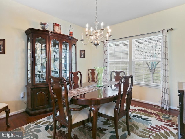 dining space featuring dark wood-style floors, visible vents, baseboards, and an inviting chandelier