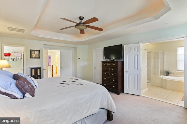 bedroom with a tray ceiling, ensuite bath, carpet flooring, and visible vents