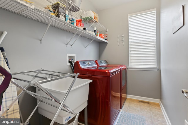 laundry room with tile patterned flooring, laundry area, separate washer and dryer, a sink, and baseboards