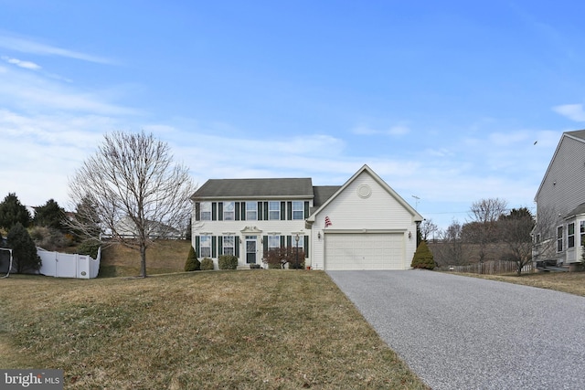 colonial house featuring a garage, driveway, a front lawn, and fence