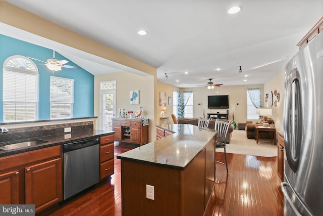 kitchen featuring appliances with stainless steel finishes, dark wood-type flooring, a sink, and a ceiling fan