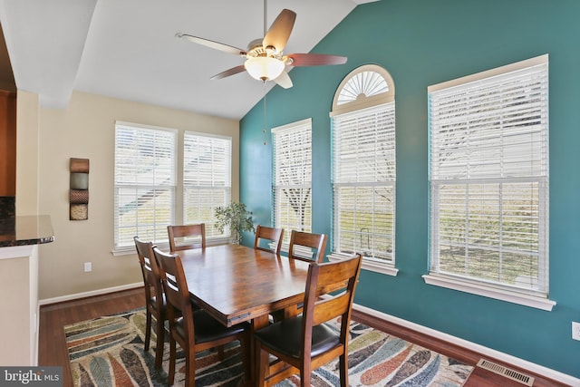 dining room featuring visible vents, vaulted ceiling, baseboards, and wood finished floors