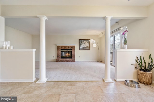 unfurnished living room featuring tile patterned floors, carpet floors, a fireplace, baseboards, and ornate columns