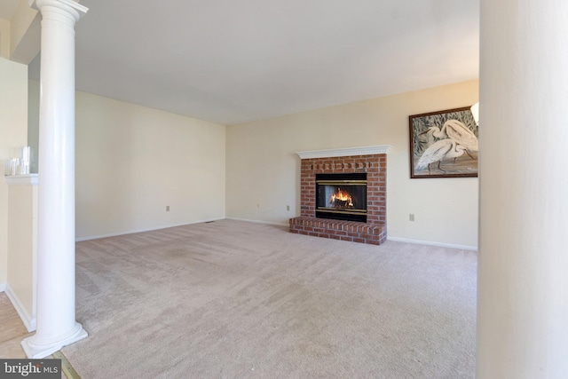 unfurnished living room with a brick fireplace, decorative columns, carpet, and baseboards