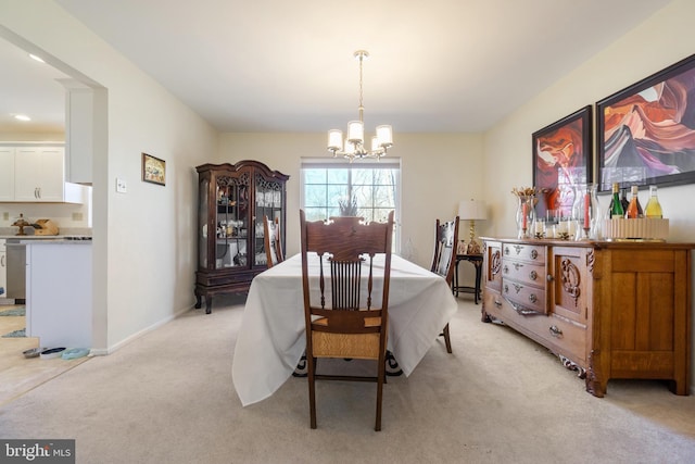 dining area featuring a notable chandelier, light colored carpet, and baseboards