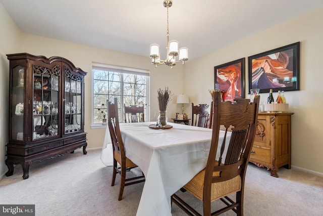 dining space featuring a notable chandelier, light colored carpet, and baseboards