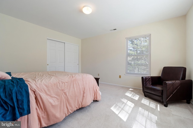 bedroom with light colored carpet, visible vents, a closet, and baseboards