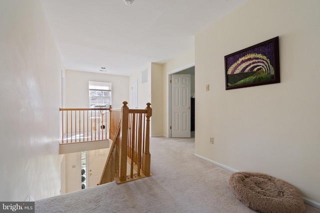 corridor featuring baseboards, visible vents, an upstairs landing, and carpet floors